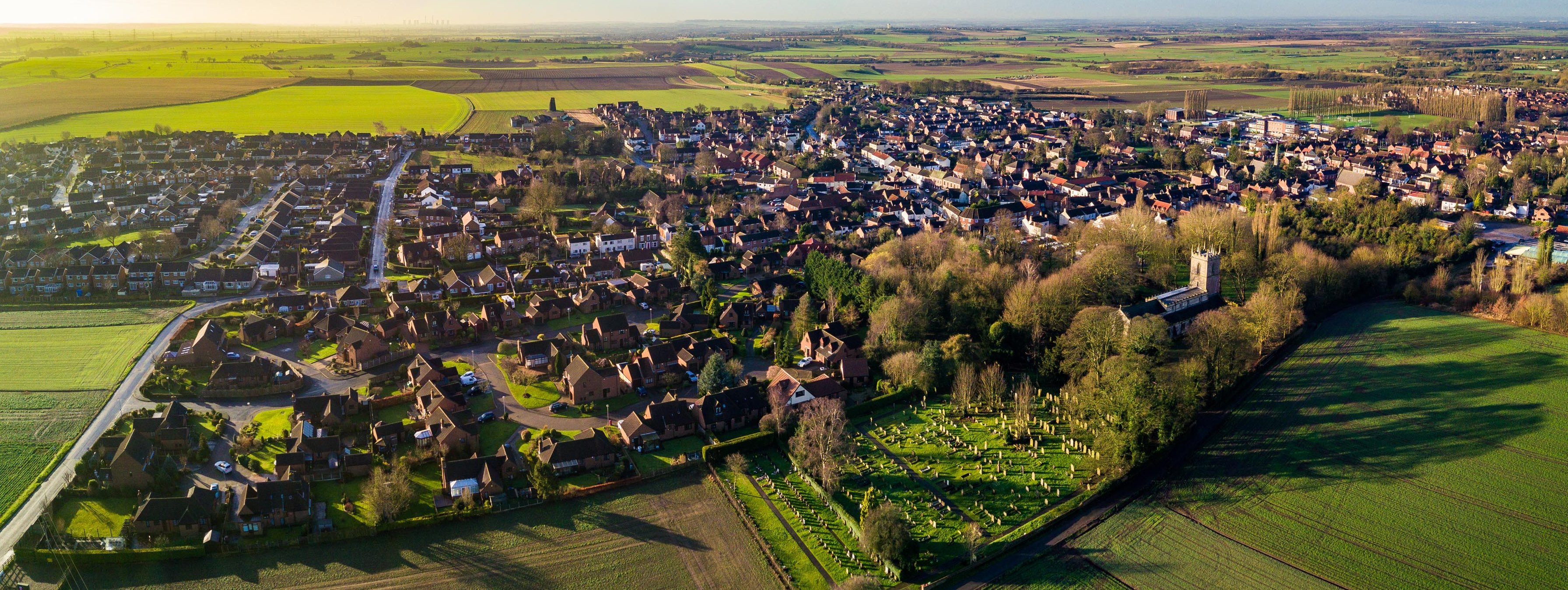 [Translate to English:] Foto aus der Luft von einem Dorf, umringt von Feldern.