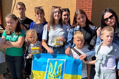 Eine Gruppe Kinder und Jugendlicher mit Ukraine-Flagge.