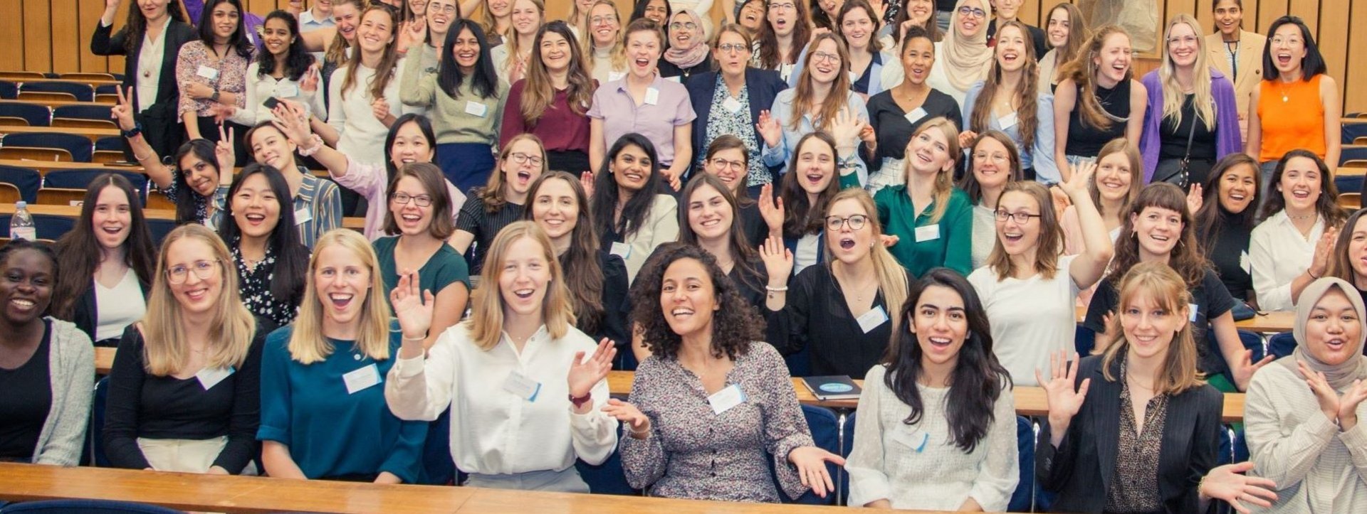 Ein Gruppenfoto von vielen Studentinnen in einem Hörsaal. Alle freuen sich.