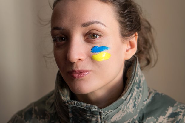 Gesicht mit zwei farbigen Streifen auf der Wange, die die ukrainische Flagge zeigen.