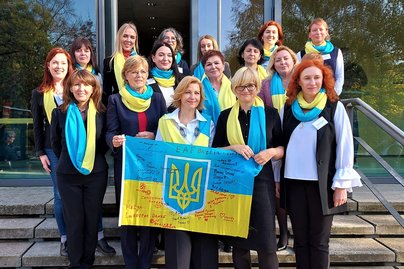 Gruppenfoto von Frauen, die blau-gelbe Schals tragen.
