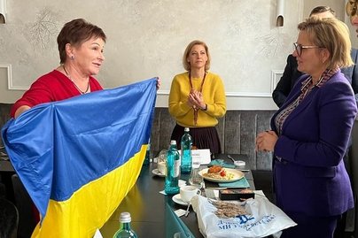 Foto von mehreren Frauen, die sich unterhalten, mit Ukraine-Flagge in der Hand.